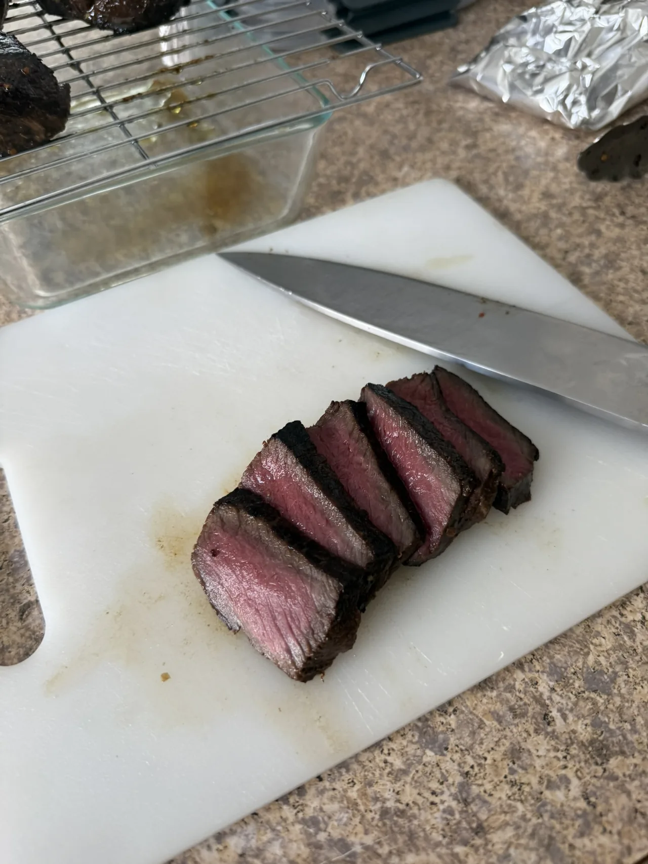 Sliced steak beside a chef knife on a cutting board